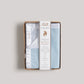 Packaged blue baby blanket with brand label on a light gray background